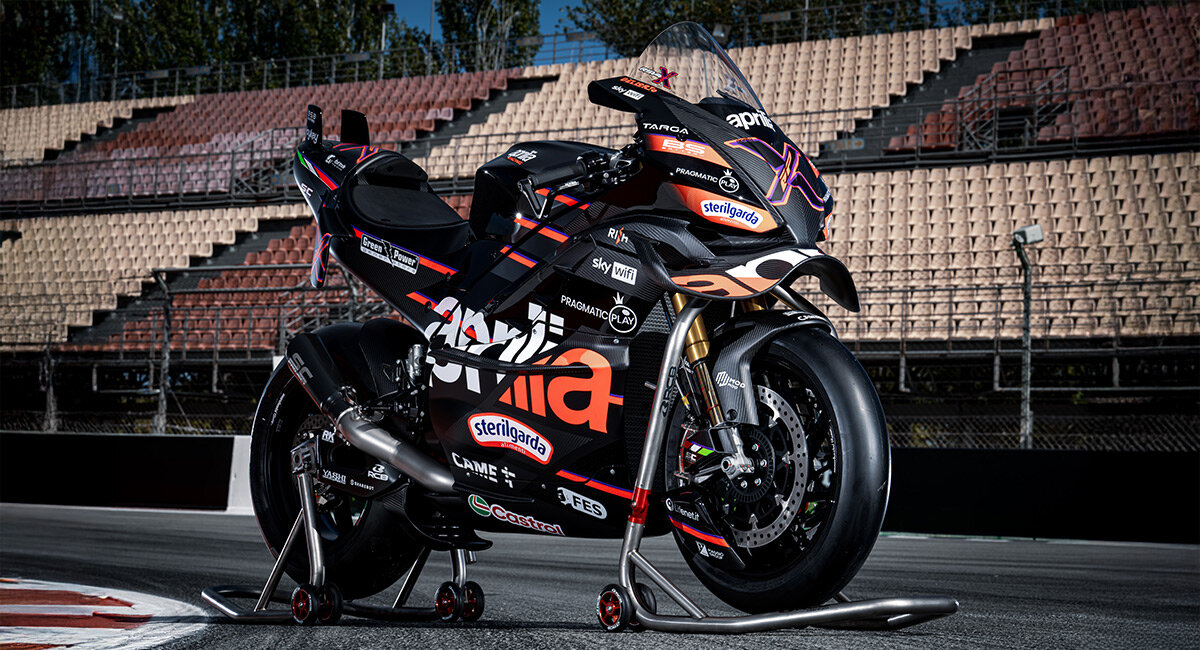 Exterior view of Aprilia Racing Noale factory with team trucks and technical building in the background