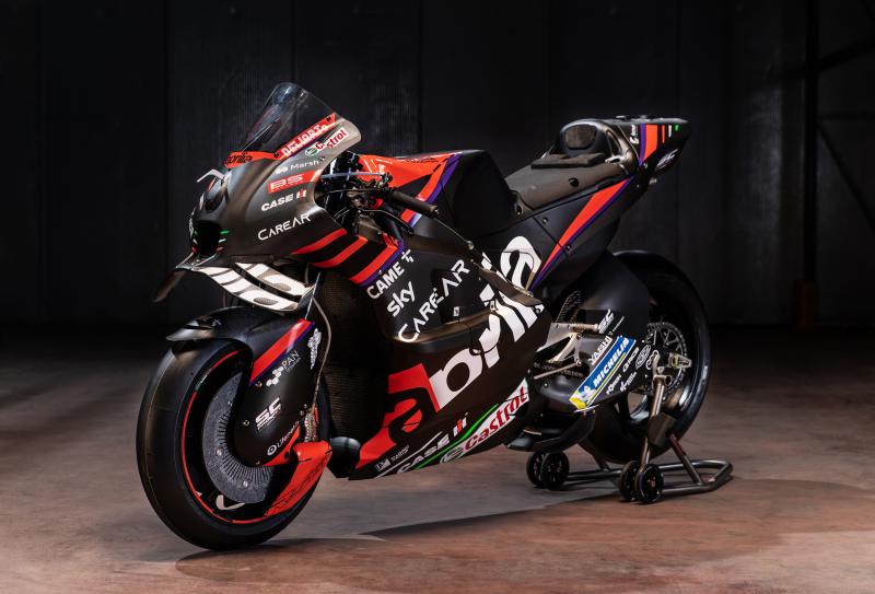 Engineers working on an Aprilia RS-GP chassis and engine components in the workshop