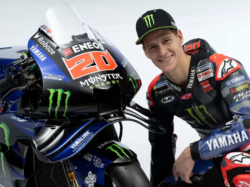 Wide view of the Monster Energy Yamaha MotoGP team garage showing mechanics, race bikes, and workstations during a race…