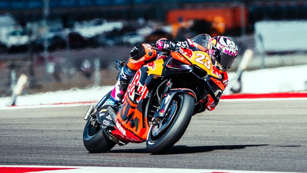 KTM MotoGP bike on track during the team's debut season, rider leaning into a corner with vibrant orange livery
