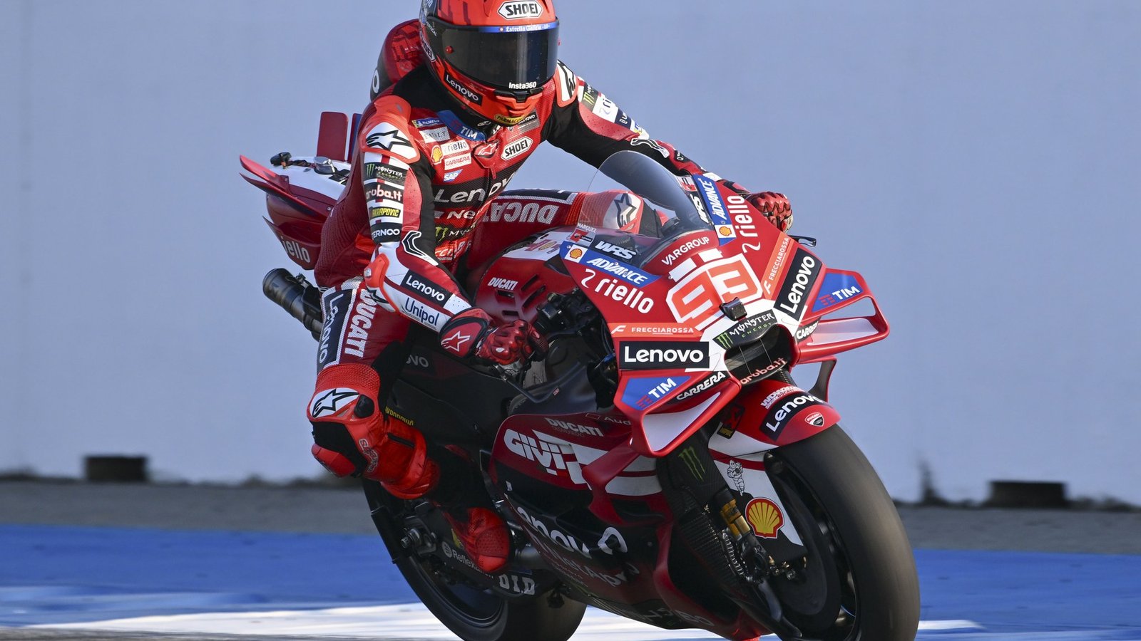 Side view of Marc Márquez trail-braking with a sharp lean angle, showing throttle control and front-end grip