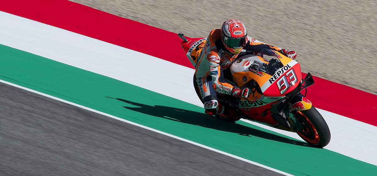 MotoGP rider braking hard into Arrabbiata corner with visible lean and front-wheel compression