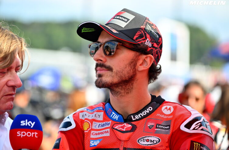 Pecco Bagnaia celebrating his Moto2 championship on the podium with his trophy and team
