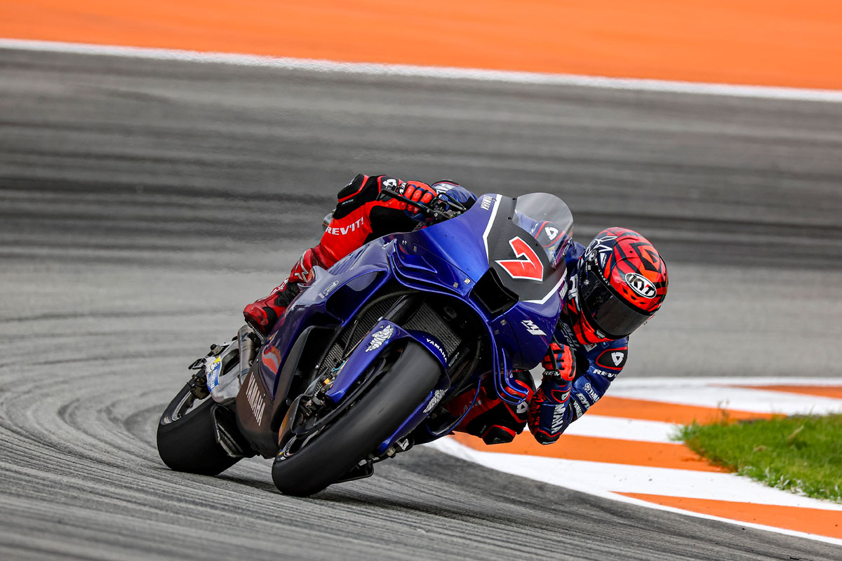Blue Yamaha MotoGP machine leaning through a fast Jerez corner with red and white kerbs and a low, loaded front end.